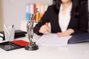 Statuette of Themis - the goddess of justice on lawyer's desk. Lawyer is stamping the document. Law office concept.